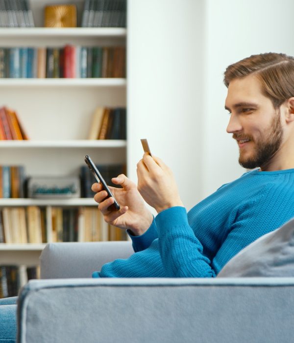 young-man-looks-at-bank-card-in-hand-and-enters-digits-to-smartphone.jpg